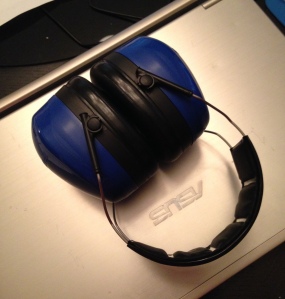 Blue noise canceling ear muffs on top of a closed laptop.